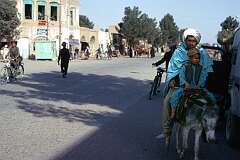 A father and his young son on a donkey in the main street of Herat.