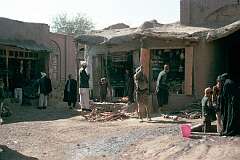 A street corner in the old city of Herat. There are open-fronted shops and a public pump where the women come to fetch water.