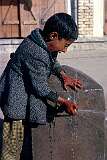 A young fellow playing at a public tap in the southern city of Kandahar. Many children had their hands painted red with henna.