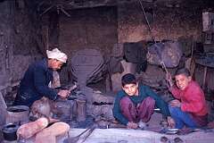 A smith's workshop in a back street of Mazar. The boys help by operating the large bellows in the background. Children often have to work at an early age.