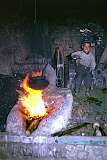 In a smith's workshop in a back street of Mazar a boy helps by operating a fan driven by a wheel. Children often have to work at an early age.