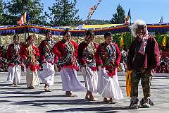 Young women perform a group dance, joined by a masked “clown”, played by a monk.
