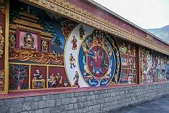 The wall on the west side of the Thupsung Dhargye Ling Monastery with colourful Buddhist paintings and bas-reliefs.