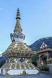 An elaborately decorated chorten (stupa), in memory of Lengka Dirkhipa, and a gate with Buddhist symbols, Thupsung Dhorgye Ling Monastery.