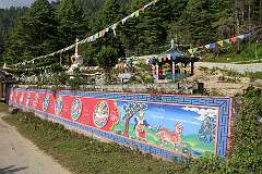 A Buddhist shrine with chorten and a wall, displaying the story of the Mongol and tiger, and other Buddhist symbols, just west of Thembang.