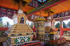 Prayer wheels and a richly decorated chorten in a shrine at Tawang Monastery.