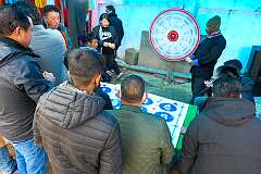 Playing a roulette game, throwing a dart at a rotating board, at the showgrounds of the festival.