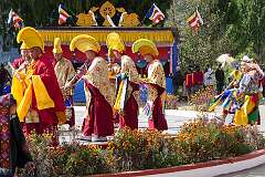 Monks with ceremonial headdresses walking onto the dancing ground, playing the Buddhist ritual reed Shawn or Gya-Ling.