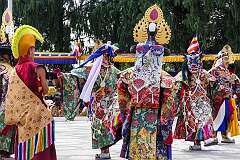 Monks with ceremonial headdresses watching a spiritual dance.