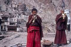 Two young monks blowing a conch shell on the flat roof of the monastery