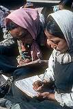 Two girls, writing during a lesson outside, at Girls' High School.