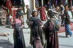 Ladakhi women in the bazaar of Leh; a tourist buying a carpet on the street.
