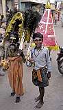 A small humpbacked man and a boy collecting donations on the street in Madurai.