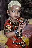 A small girl, her head shaved as a dedication to Shiva and covered with tumeric near the Murungan temple in the town of Palani.