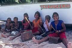 Children drumming on tins on the beach in Betio.