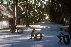 Children playing with tyres in a village street on Betio.